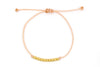 Armband aus pfirisch farbenem Makramee und 10 goldenen Perlen aus 925 Silber auf weißem Hintergrund