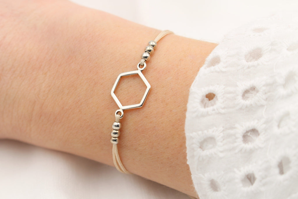 beiges Makramee Armband mit silberfarbenem Hexagon und 6 kleinen Perlen am Handgelenk getragen