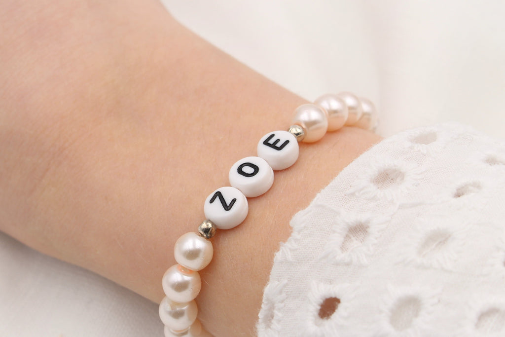 Perlenarmband mit Namen in rosa perlmutt am Handgelenk getragen