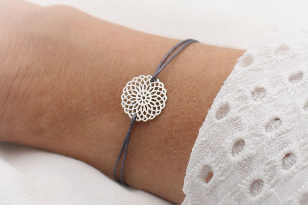 dunkel graues Armband mit silberner Blume im Bohostyle am Handgelenk getragen