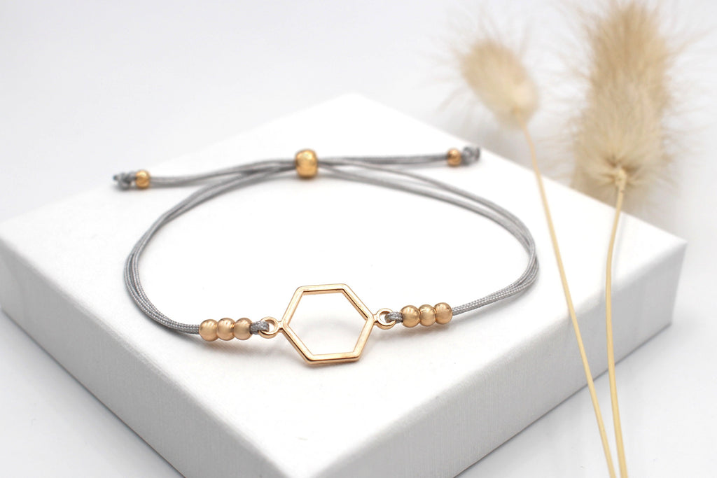 hell graues Makramee Armband mit sechseck Symbol und 6 kleinen Perlen neben dem Hexagon und verstellbarem Kugelverschluss