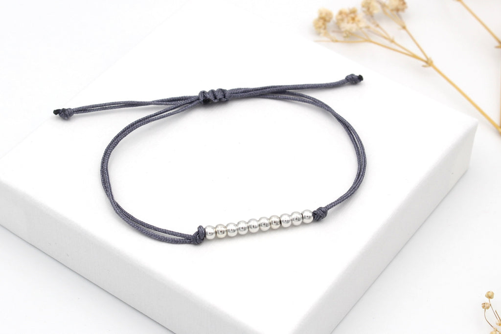 Perlenarmband aus 10 Perlen und einem grauen Makramee Band