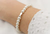 ivory farbenes Perlen Armband mit Fisch in silber, am Handgelenk der Dame getragen