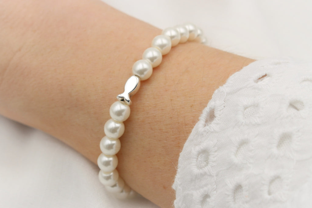ivory farbenes Perlen Armband mit Fisch in silber, am Handgelenk der Dame getragen