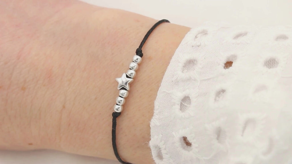 Video schwarzes Armband Makramee mit Stern und Perlen in silberfarben an einem Handgelenk getragen