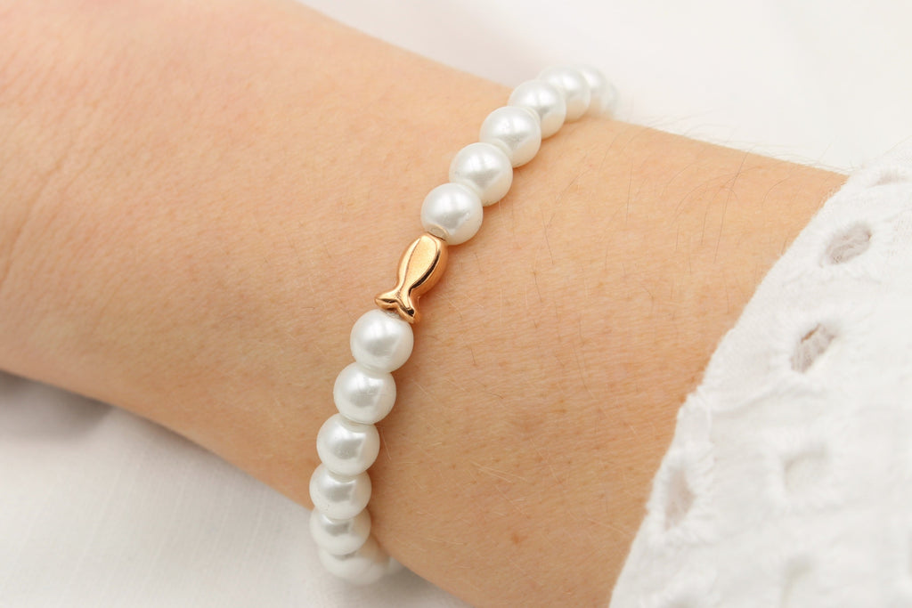 martimes Armband mit Perlen und Fisch in rosegold am Handgelenk des Mädchens getragen