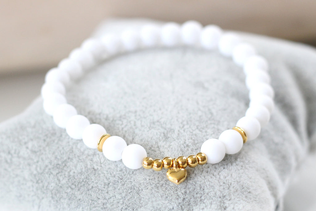 weißes Perlenarmband mit goldfarbenen Herz Anhänger und zarten Details