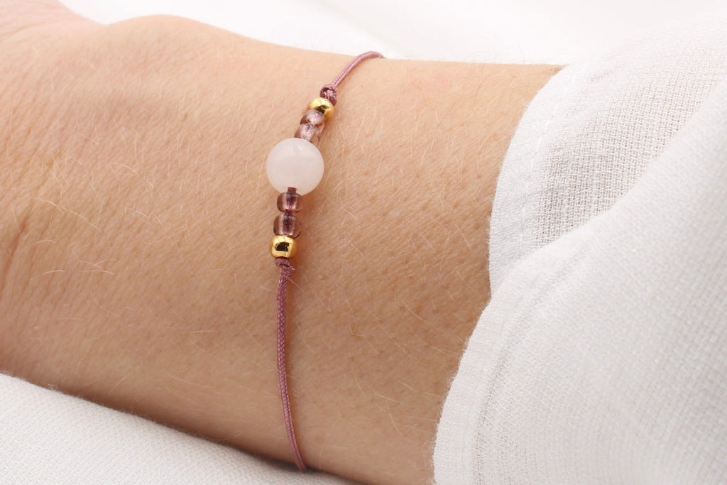 zartes Armband aus Makramee und Halbedelstein Perle Jade in hell rosa am Handgelenk getragen mit Bandfarbe in Beerentönen