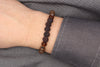 Herrenarmband aus braun schwarzen Perlen mit silberfarbigen Details am Handgelenk des Mannes getragen