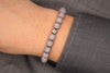 Buddha Armband Herren als Perlenarmband in hell grau am Handgelenk des Mannes getragen