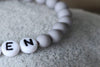 Details Namensarmband in grau mit weißen Buchstaben