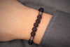 Herrenarmband aus schwarzen Lavaperlen und Holzperlen mit grauen Details am Handgelenk des Mannes getragen als Geschenkidee zum Vatertag