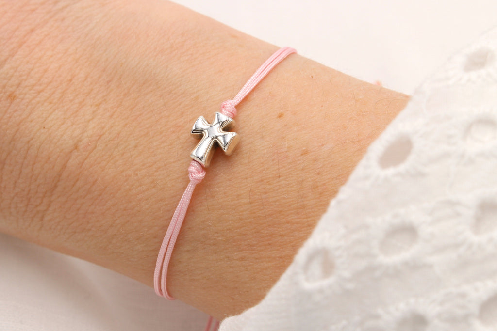 Rosanes Makramee Armband mit silbernem Kreuz am Handgelenk getragen als Kommunion Geschenk für Mädchen