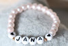 Armband mit Name aus rosa Perlen mit 2 weißen Herzen neben deiner Personalisierung