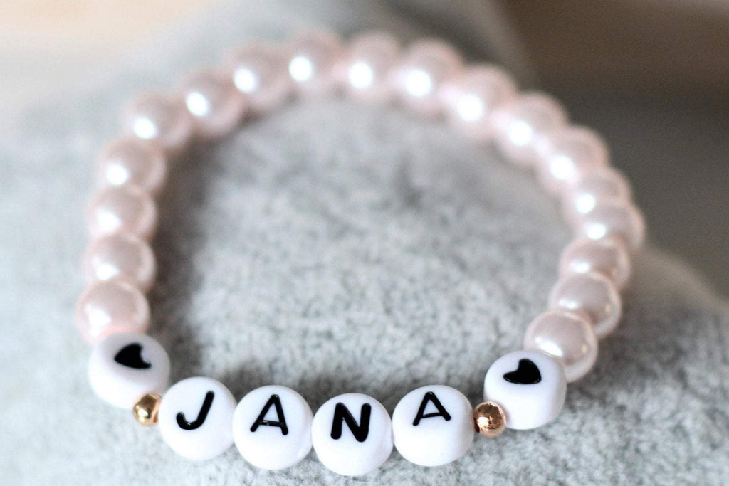 Armband mit Name aus rosa Perlen mit 2 weißen Herzen neben deiner Personalisierung